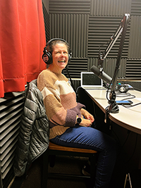 a smiling woman wearing headphones in the recording studio