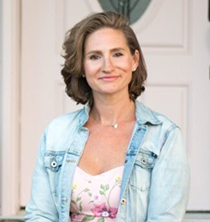a woman in a jean jacket smiles at the viewer